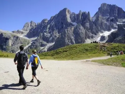 two people walking down a dirt road in the mountains at Apartment Elegantes und geräumiges Dachgeschosszimmer in den Dolomiten by Interhome in Mezzano