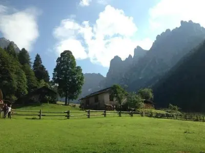 a field with a fence and mountains in the background at Apartment Elegantes und geräumiges Dachgeschosszimmer in den Dolomiten by Interhome in Mezzano