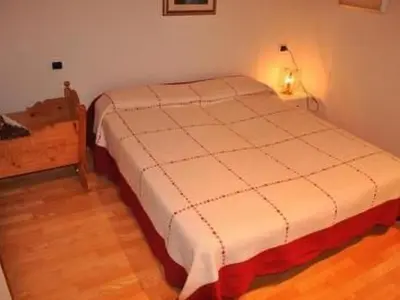 a bedroom with a white bed with a light on it at Apartment Elegantes und geräumiges Dachgeschosszimmer in den Dolomiten by Interhome in Mezzano