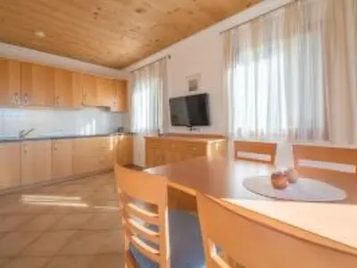 a kitchen with a table and chairs and a television at Apartment mit traumhaftem Ausblick by Interhome in Siusi