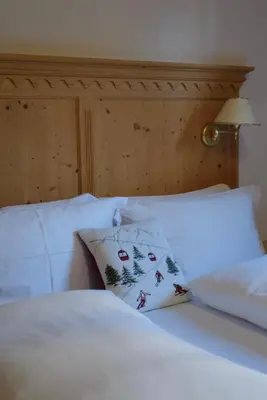 a bed with white sheets and a pillow on it at Luxury Chalet at the Foot of the Dolomites by the Castle in La Villa