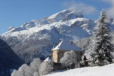 a building in the snow with a snow covered mountain at Luxury Chalet at the Foot of the Dolomites by the Castle in La Villa