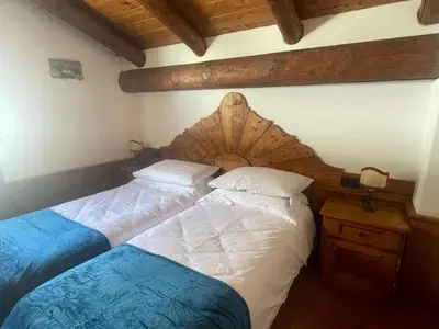 a bedroom with two beds and a wooden headboard at Chalet Alba in Cortina dʼAmpezzo