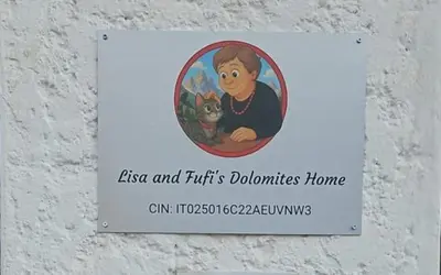 a sign on a wall with a woman holding a cat at Lisa & Fufi's Dolomites Home in Cortina dʼAmpezzo