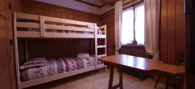 a bedroom with two bunk beds and a wooden table at Lisa & Fufi's Dolomites Home in Cortina dʼAmpezzo