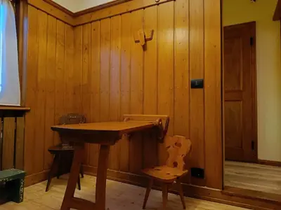 a wooden table and a chair in a room at Lisa & Fufi's Dolomites Home in Cortina dʼAmpezzo