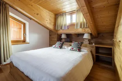 a bedroom with a white bed in a log cabin at Chalet Lacedel - Dolomiti Skyline in Cortina dʼAmpezzo