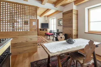 a living room with a table and a kitchen at Chalet Lacedel - Dolomiti Skyline in Cortina dʼAmpezzo