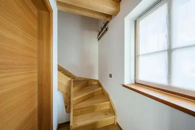 a wooden staircase in a house with a window at Chalet Lacedel - Dolomiti Skyline in Cortina dʼAmpezzo