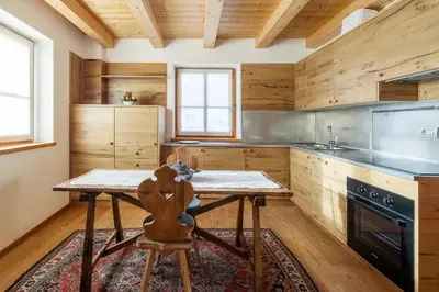 a kitchen with wooden walls and a wooden table with a chair at Chalet Lacedel - Dolomiti Skyline in Cortina dʼAmpezzo