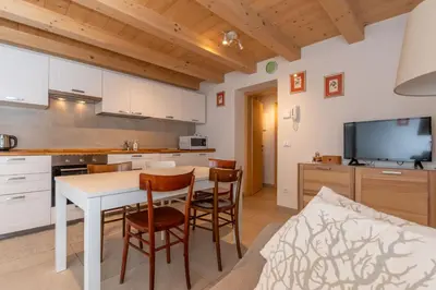 a kitchen and living room with a table and chairs at Ciasa al Caselo in Falcade