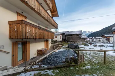 a house with a wooden balcony and a table at Ciasa al Caselo in Falcade