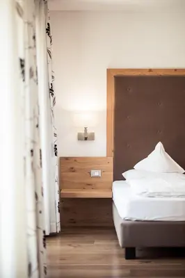 a bedroom with a white bed and a wooden headboard at Torgglerhof in Schenna