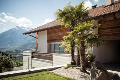 a house with a balcony with palm trees at Torgglerhof in Schenna