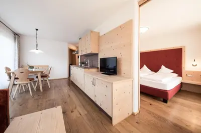 a bedroom with a bed and a desk with a tv at Torgglerhof in Schenna