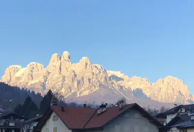 a snow covered mountain in front of a town with houses at Vacanza in relax in Mezzano