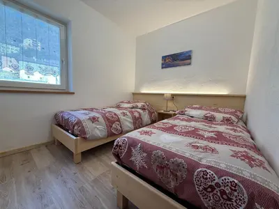 a bedroom with two beds and a window at Mountain Breeze in Castello di Fiemme