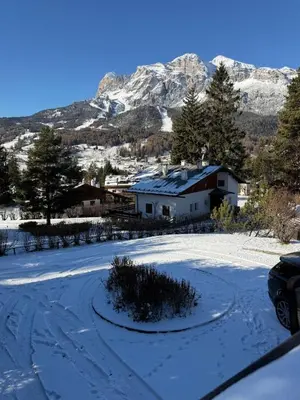 a snow covered yard with a house and a mountain at Casa panoramica con terrazza vista Tofane in Cortina dʼAmpezzo