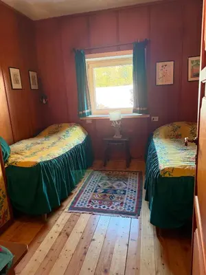 two beds in a room with a window and a rug at Casa panoramica con terrazza vista Tofane in Cortina dʼAmpezzo