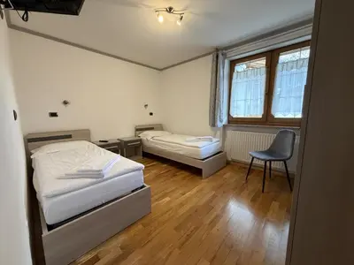 a bedroom with two beds and a chair in it at Appartamento Star Begn - Piano Terra in Soraga