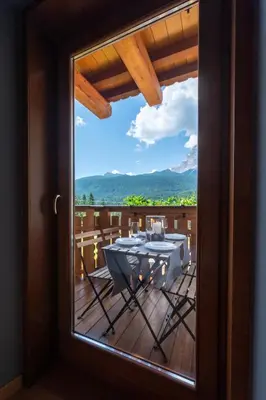 a view from a door of a table on a deck at Olympic Comfy Trimestate Ampezzo s Flat in San Vito di Cadore