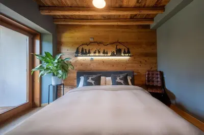 a bedroom with a large bed with a wooden wall at Olympic Comfy Trimestate Ampezzo s Flat in San Vito di Cadore