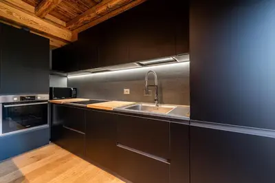a kitchen with black cabinets and a sink at Olympic Comfy Trimestate Ampezzo s Flat in San Vito di Cadore