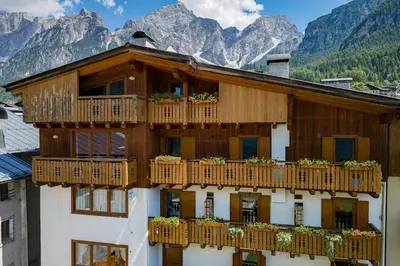 a building with wooden balconies with flowers on it at Olympic Comfy Trimestate Ampezzo s Flat in San Vito di Cadore
