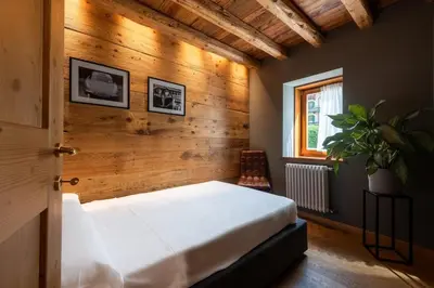 a bedroom with a white bed and a wooden wall at Olympic Comfy Trimestate Ampezzo s Flat in San Vito di Cadore