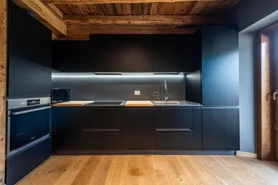 a kitchen with black cabinets and a wooden ceiling at Olympic Comfy Trimestate Ampezzo s Flat in San Vito di Cadore
