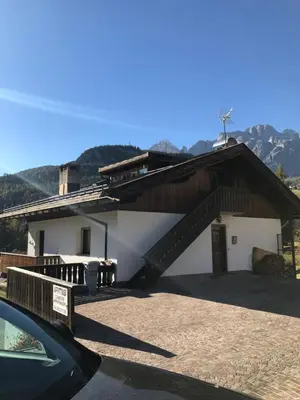 a white building with a wooden roof and a staircase at Ciasa Nonna Bon Bon in Cortina dʼAmpezzo