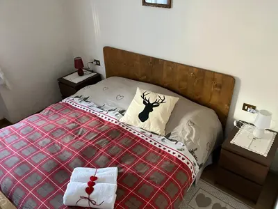 a bedroom with a bed with a red blanket and two night stands at Ciasa Nonna Bon Bon in Cortina dʼAmpezzo