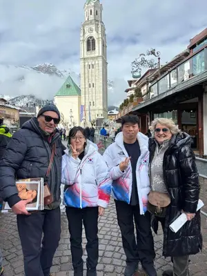 a group of people standing on a street with a clock tower at Ciasa Nonna Bon Bon in Cortina dʼAmpezzo