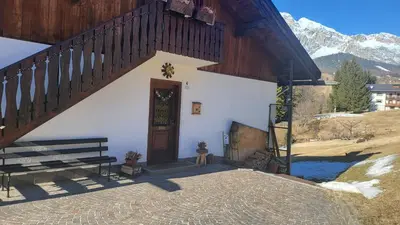a building with a wooden door and a bench at Ciasa Nonna Bon Bon in Cortina dʼAmpezzo