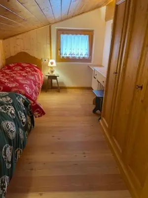a small room with a bed and a table and a window at Chalet Luxury Pelmo in San Vito di Cadore