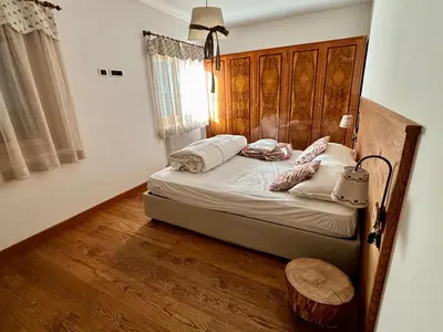 a bedroom with a bed with a wooden headboard at 70 sqm apartment in Moena in Moena