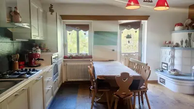 a kitchen with a table and chairs and a kitchen with a stove at 70 sqm apartment in Moena in Moena
