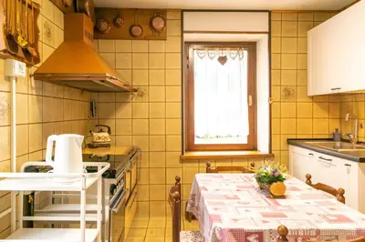 a small kitchen with a table and a window at Casa tipica nelle Dolomiti Trentine in Mezzano