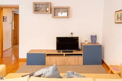 a living room with a flat screen tv on a cabinet at Casa tipica nelle Dolomiti Trentine in Mezzano