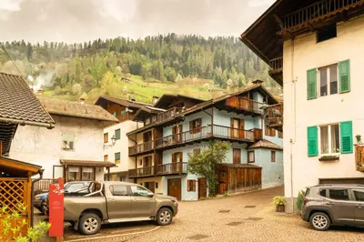 a group of buildings with cars parked on a street at Casa tipica nelle Dolomiti Trentine in Mezzano