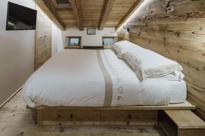 a large bed in a room with a wooden wall at Cortina Penthouse Attico Villa Diana in Pocol