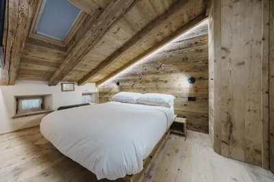 a large bed in a room with wooden walls at Cortina Penthouse Attico Villa Diana in Pocol