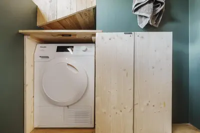a washer and dryer in a bathroom with a wooden wall at Cortina Penthouse Attico Villa Diana in Pocol