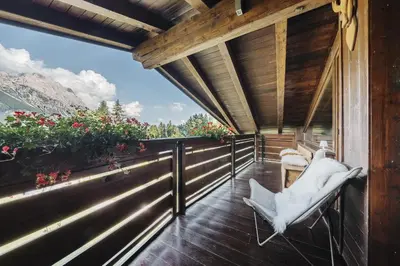 a balcony of a house with a chair and flowers at Cortina Penthouse Attico Villa Diana in Pocol