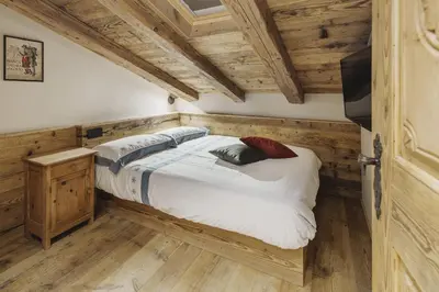 a bedroom with a bed in a room with wooden ceilings at Cortina Penthouse Attico Villa Diana in Pocol