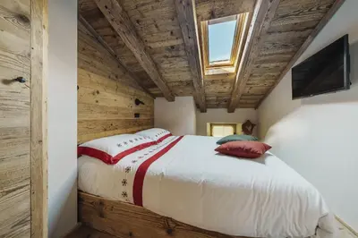 a bed in a room with a wooden ceiling at Cortina Penthouse Attico Villa Diana in Pocol
