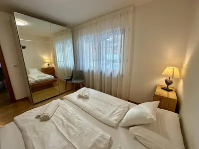 a bedroom with a bed with white sheets and a mirror at Central Dolomites Atelier - 3 Bedrooms in Campitello di Fassa