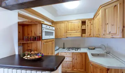 a kitchen with wooden cabinets and a bowl of fruit on a counter at HouSmart della Difesa 72 in San Vito di Cadore