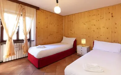 two beds in a room with wooden walls and a window at HouSmart della Difesa 72 in San Vito di Cadore