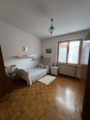 a bedroom with a bed and two windows and a wooden floor at Il sole di Varena in Varena